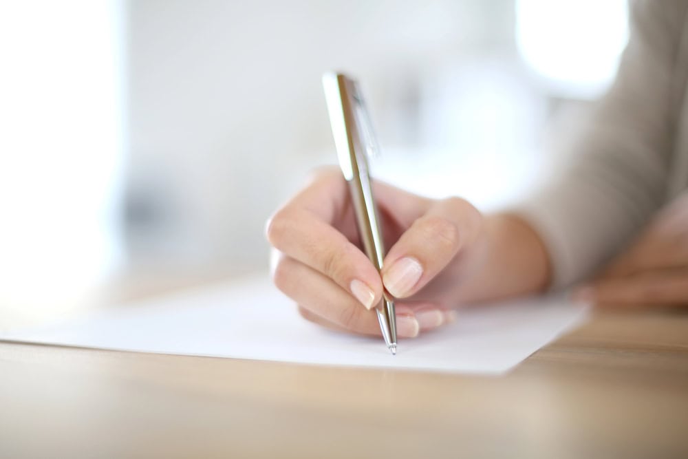 Press release checklist: the ultimate 2025 guide 2 A woman's hand writing on paper